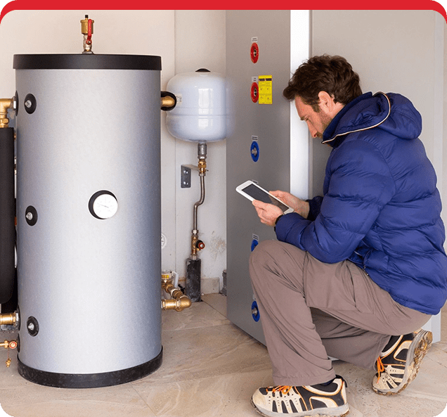 A man is using his tablet in front of an electric water heater.