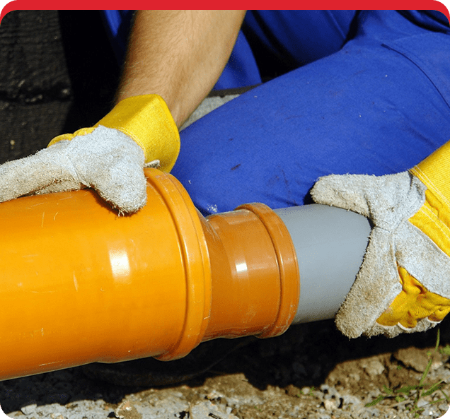 A person in blue shirt and yellow gloves holding pipe.