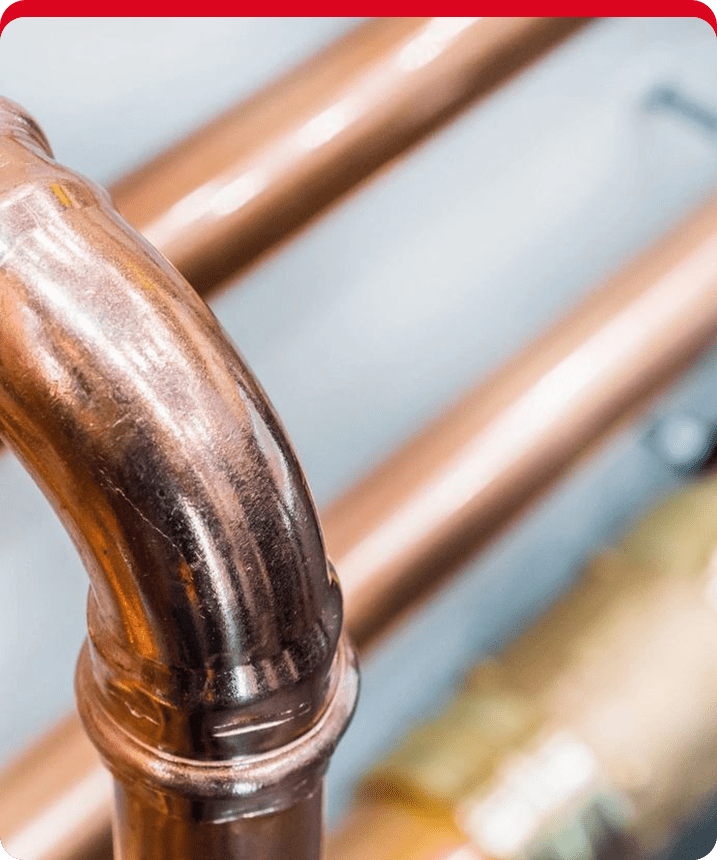 A close up of the copper pipe on the side of a wall.