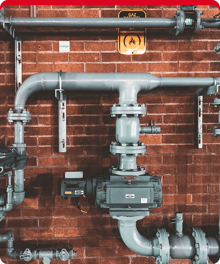 A red brick wall with pipes and valves.