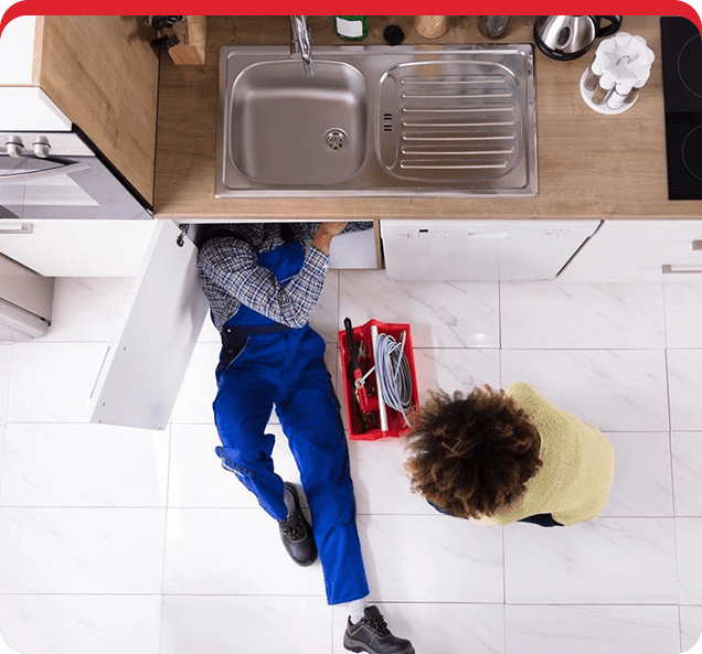 A person laying on the floor in front of a sink.