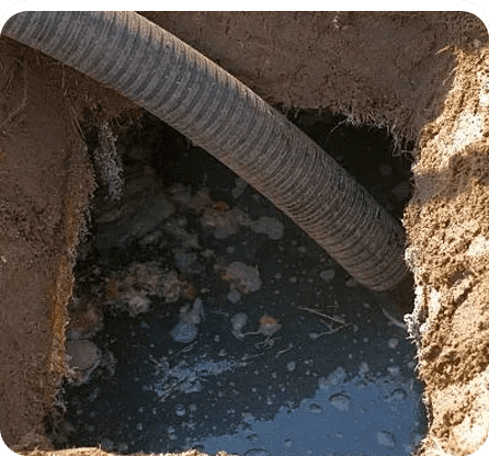 A pipe is in the ground near some water.