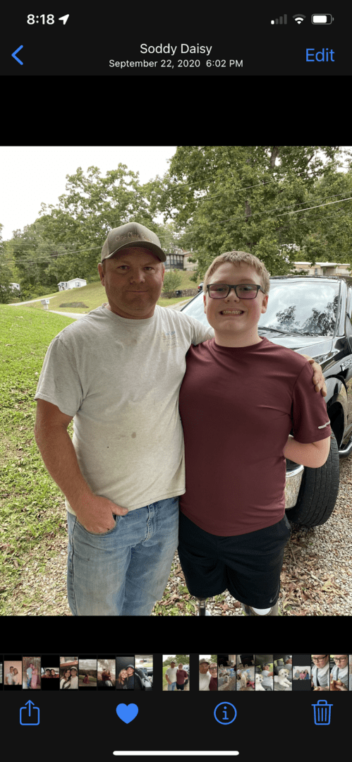 Two men standing next to a black car.