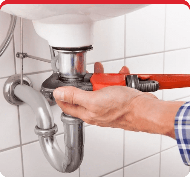 A person fixing the pipes of a bathroom sink.