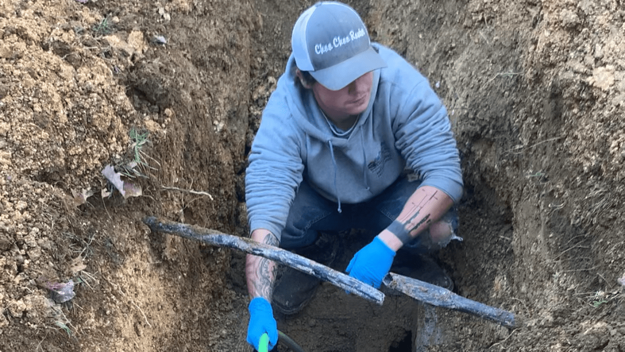 A man in blue gloves is digging holes.