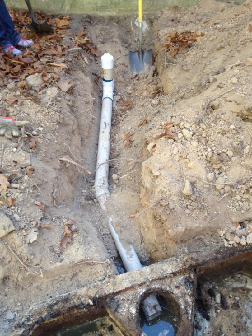 A pipe is laying in the ground on top of rocks.